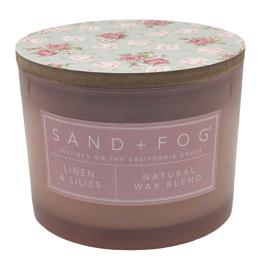 Linen & Lillies scented candle with floral lid and 'Sand + Fog' label on a white background