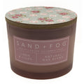 Linen & Lillies candle with floral lid and 'Sand + Fog' label on a white background