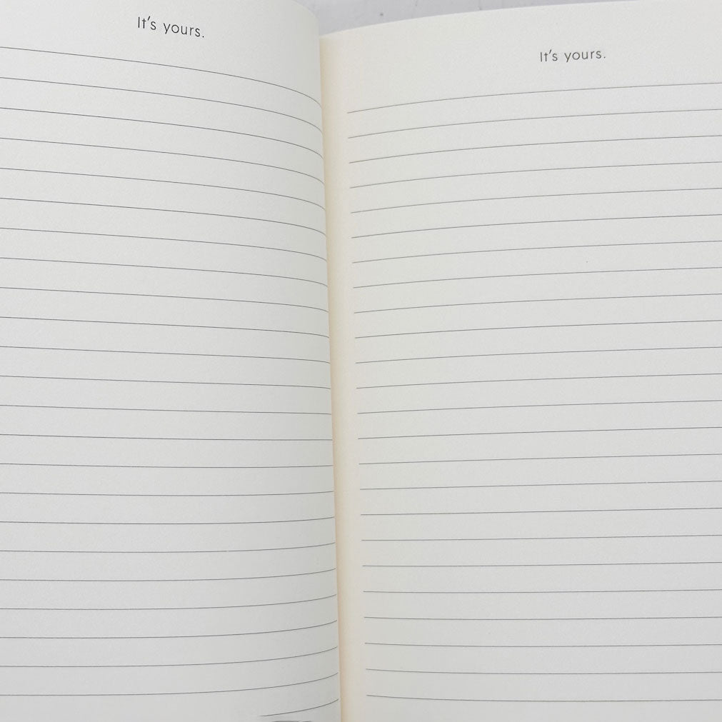 Open notebook with lined pages and 'it's yours.' text on a white background
