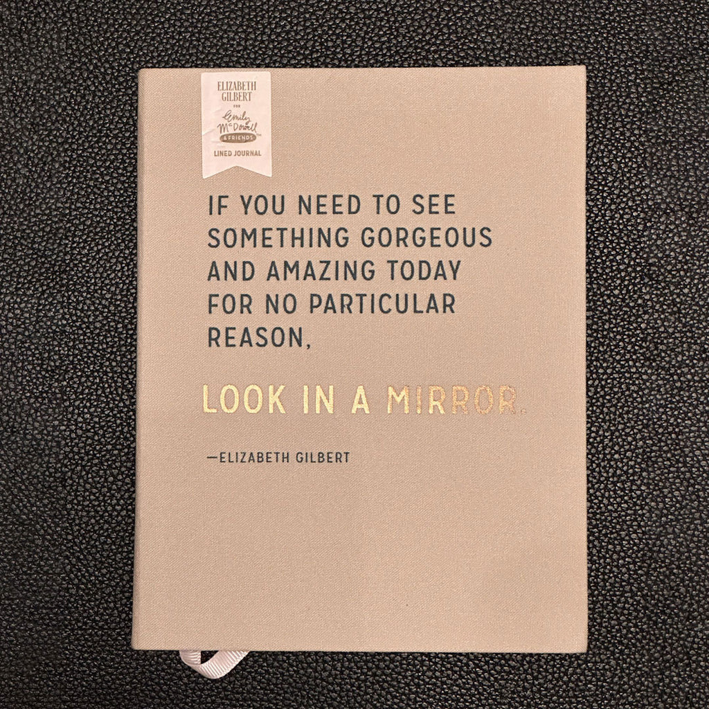 Notebook with a quote by Elizabeth Gilbert on a textured black background