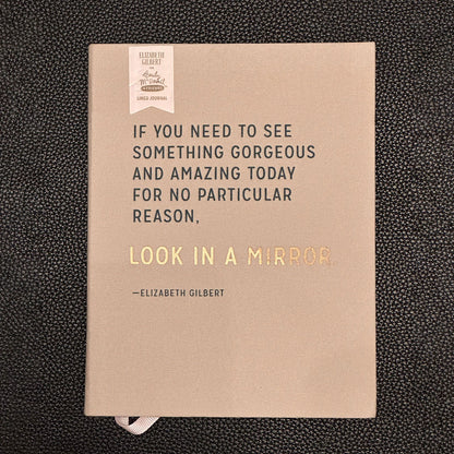 Notebook with a quote by Elizabeth Gilbert on a textured black background