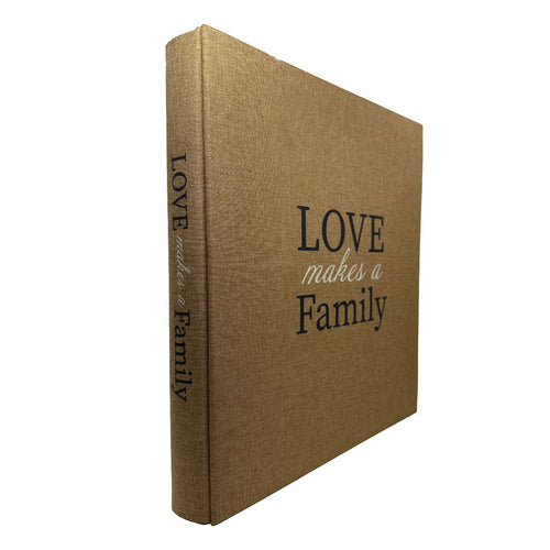 A hardcover photo album with a textured tan linen cover and black printed text reading 'LOVE makes a Family' on the front cover and spine, shown on a plain white background.