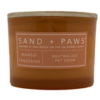 Mango Tangerine brown candle with 'Sand + Paws' label on a white background