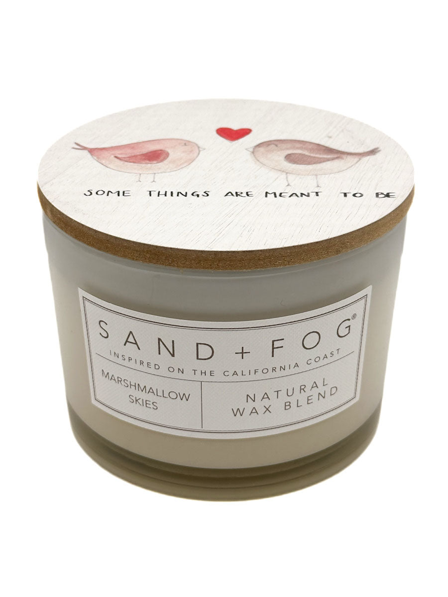Marshmallow Skies Candle with decorative lid featuring birds and text, branded 'Sand + Fog'.