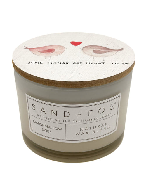 Marshmallow Skies Candle with decorative lid featuring birds and text, branded 'Sand + Fog'.