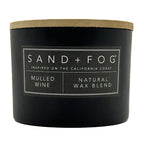 Mulled wine black candle with a wooden lid labeled 'Sand + Fog' on a white background