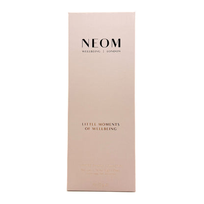 A tall, narrow pale blush pink box with black and rose-gold text reading 'NEOM WELLBEING | LONDON' and 'LITTLE MOMENTS OF WELLBEING', centered on a white background.