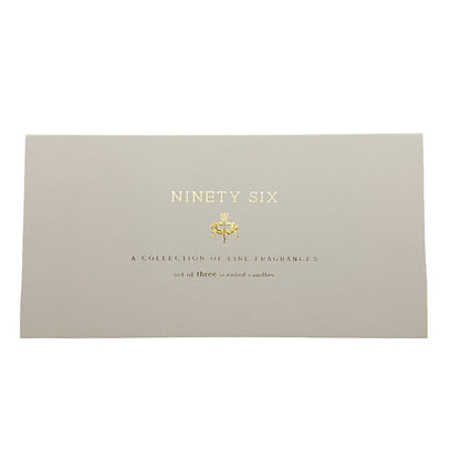 A rectangular beige candle gift box cover with gold foil text reading 'NINETY SIX' and smaller text below, photographed on a plain white background.