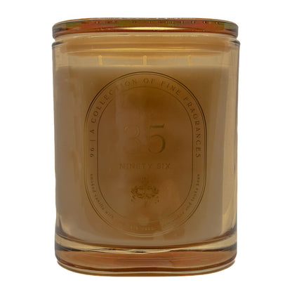A No. 35 35 DW Home scented candle in a translucent amber glass jar with a gold-toned metal lid, featuring an embossed oval label on the front.