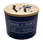Ocean Mist candle container with wooden lid featuring 'SAND + PAWS' branding on a white background