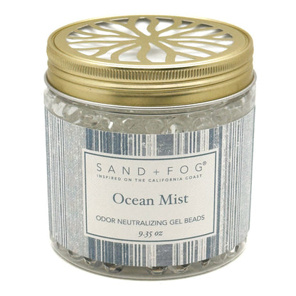 A jar of Sand + Fog Ocean Mist odour neutralising gel beads, featuring a metallic gold lid with a decorative cutout and a grey-white label.