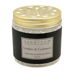 A jar of Sand + Fog Leather & Cashmere odor neutralizing gel beads, featuring a black textured label and a gold metal lid with a decorative cutout pattern, set against a plain white background.