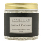 A jar of Sand + Fog Leather & Cashmere odor neutralizing gel beads, featuring a black label and a gold metal lid, filled with clear gel beads.