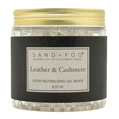 A jar of Sand + Fog Leather & Cashmere odor neutralizing gel beads, featuring a black label and a gold metal lid, filled with clear gel beads.