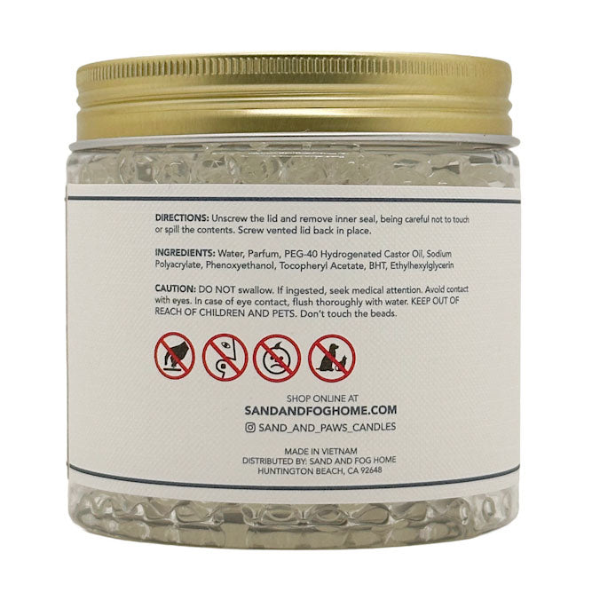 A clear plastic jar of Sand and Fog Home BHT Ethylhexyrgron candle beads with a gold screw-on lid and a white label showing product directions and ingredients.