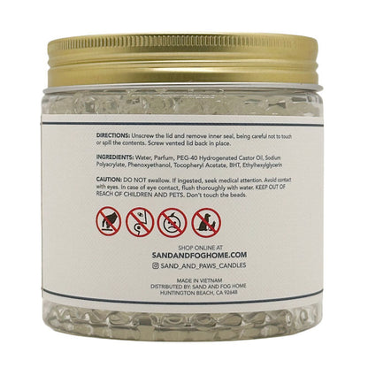 A clear plastic jar of Sand and Fog Home BHT Ethylhexyrgron candle beads with a gold screw-on lid and a white label showing product directions and ingredients.