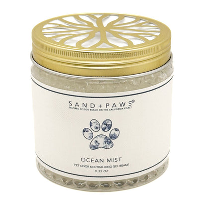 A jar of Sand + Paws Ocean Mist pet odor neutralizing gel beads with a gold metal lid and white label, set against a plain white background.