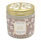 A glass jar of Sand+Fog Fresh Cotton odour neutralising gel beads with a gold metal lid and a dusty pink label decorated with cotton bolls.