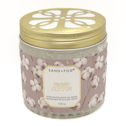 A glass jar of Sand+Fog Fresh Cotton odour neutralising gel beads with a gold metal lid and a dusty pink label decorated with cotton bolls.