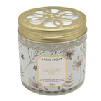 A jar of Sand + Fog Laundry Day odour neutralising gel beads with a gold perforated lid and a floral-patterned label, set against a plain white background.