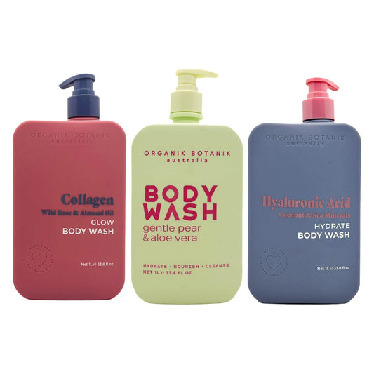 Three body wash bottles from Organik Botanik Australia lined up against a white background: a coral pink bottle labeled Collagen, a pale yellow-green bottle labeled BODY WASH, and a slate blue bottle labeled Hyaluronic Acid.