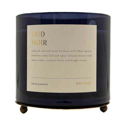 A dark navy blue glass jar candle with a cream-coloured label reading 'OUD NOIR' and 'DW HOME', shown on a plain white background.