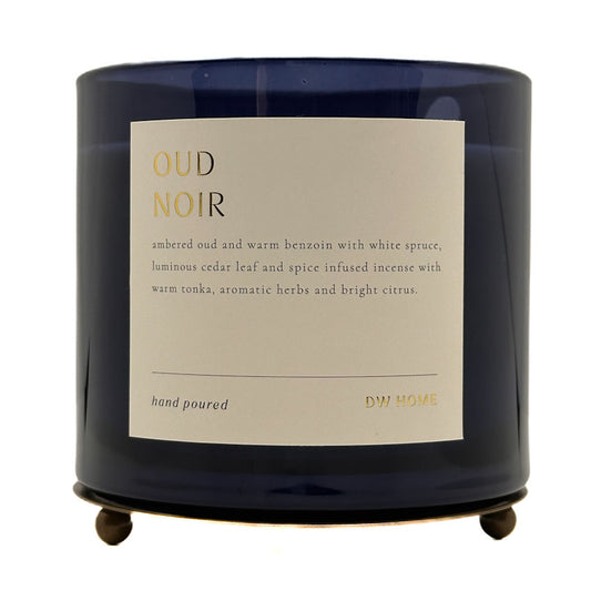 A dark navy blue glass jar candle with a cream-coloured label reading 'OUD NOIR' and 'DW HOME', shown on a plain white background.