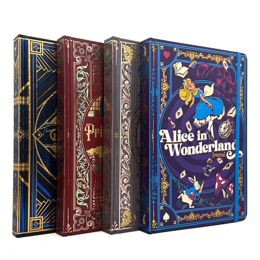 Four decorative hardcover journal covers arranged upright on a white background, featuring Alice in Wonderland themed artwork and ornate embossed-style designs in blue, burgundy, gray-gold, and dark blue with gold detailing.