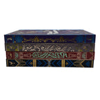 A stack of four decorative book-style boxes with ornate embossed or printed spines in dark blue, olive green, burgundy, and black, featuring gold and teal detailing, on a plain white background.