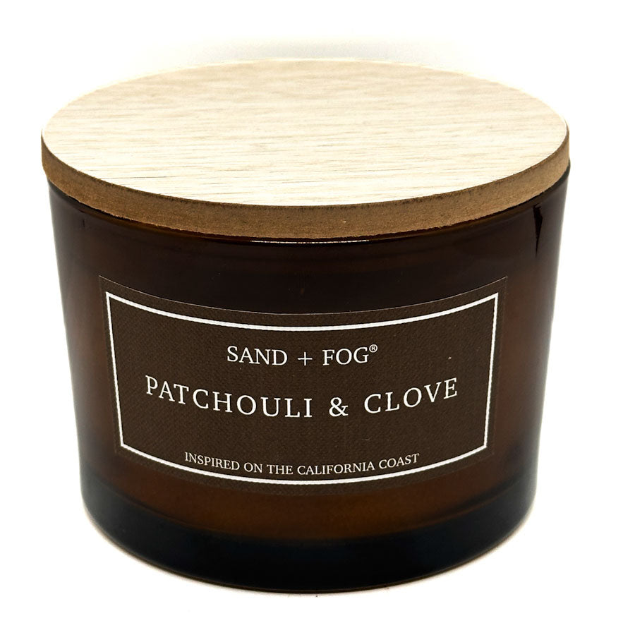 Candle with wooden lid labeled 'Patchouli & Clove' by Sand + Fog on a white background