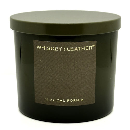 A green scented candle jar with a green lid, labeled 'WHISKEY & LEATHER', indicating the scent of the candle.