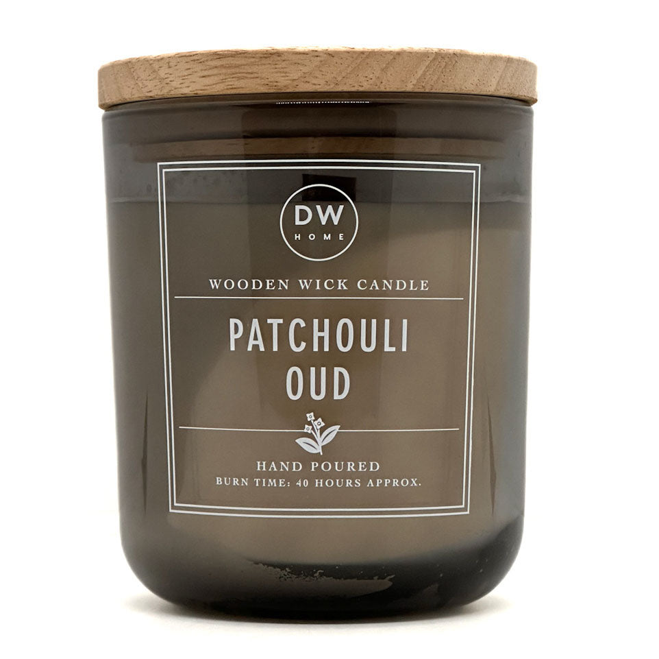 A dark amber glass jar candle with a light natural wood lid and a white label reading 'DW HOME' and 'PATCHOULI OUD'.