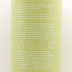 Back of a green bottle with text and product details on a white background