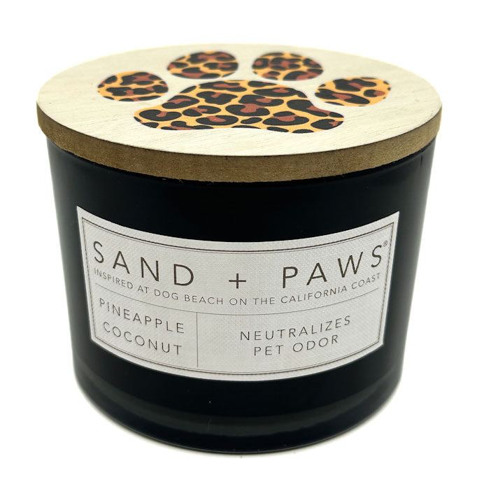 Pineapple Coconut candle labeled 'Sand + Paws' with a leopard print lid on a white background