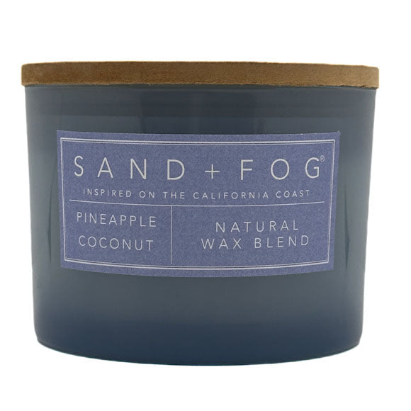 Pineapple Coconut blue candle with 'Sand + Fog' label on a white background