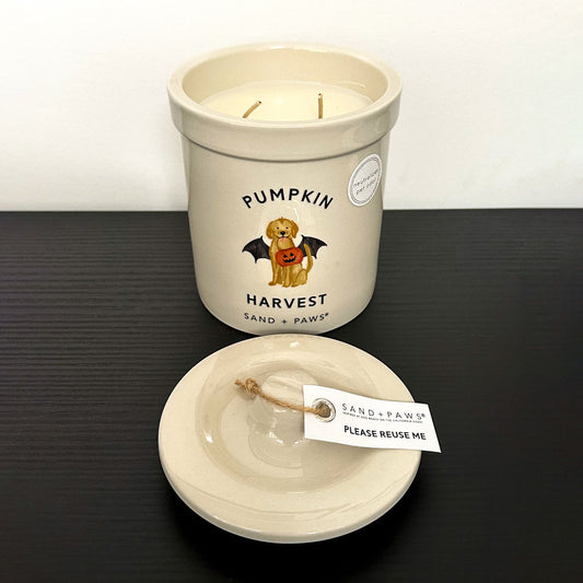 Candle with 'Pumpkin Harvest' label and lid on a dark surface