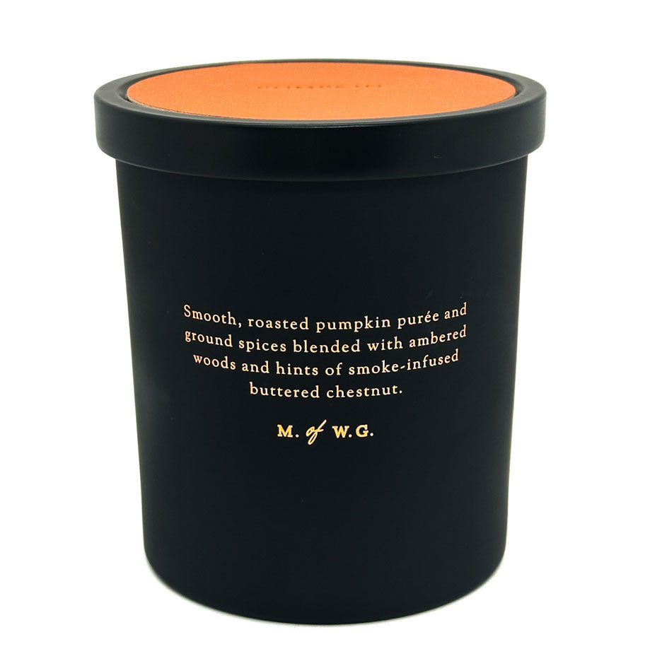 M. of W.G. Pumpkin black candle container with orange lid featuring text on a white background