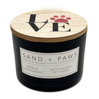 Roses & Sandalwood Black candle with a wooden lid featuring 'LOVE' and paw prints, branded 'Sand + Paws'.