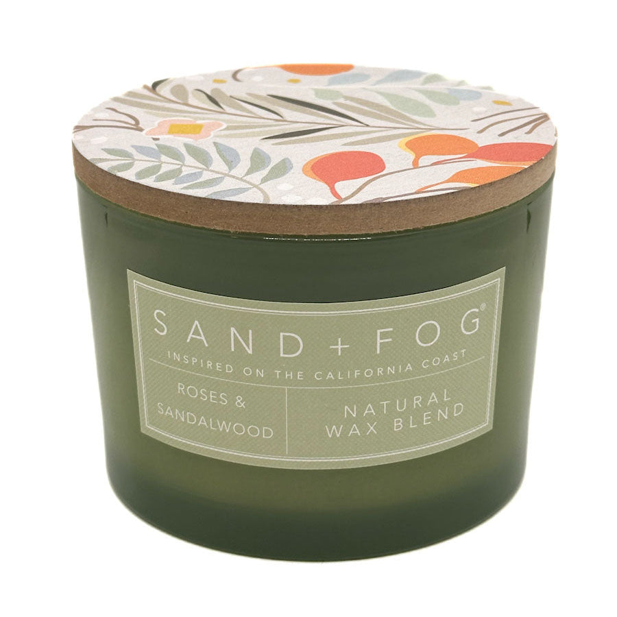 Roses & Sandalwood Green candle with floral lid labeled 'Sand + Fog' on a white background