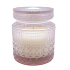 Decorative candle in a textured glass jar with a white lid on a white background