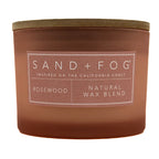 Rosewood rose candle with 'Sand + Fog' label on a white background