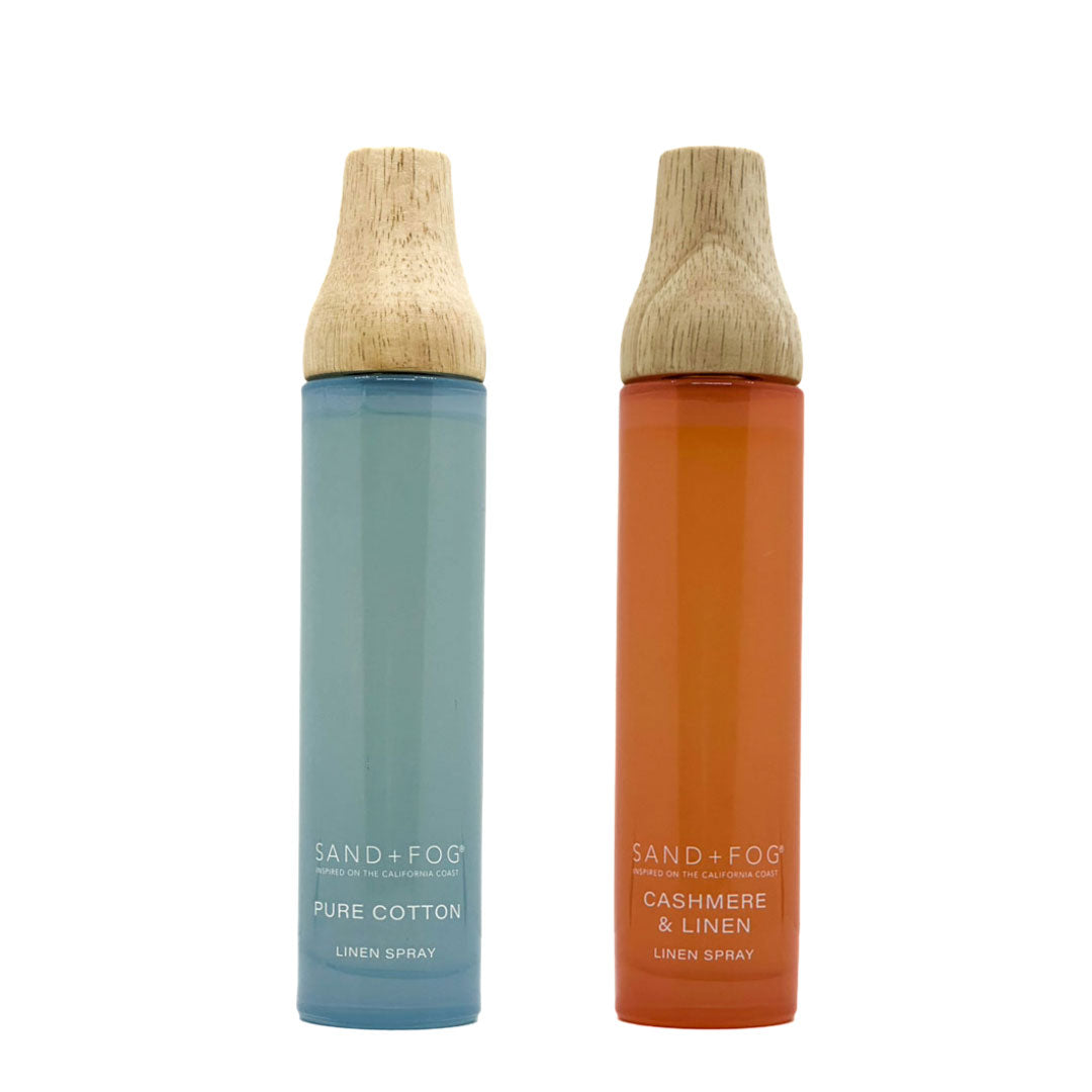 Two bottles of Sand + Fog linen spray with wooden nozzles on a white background.