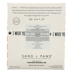 Back of a Sand + Paws candle packaging box with product details and branding.
