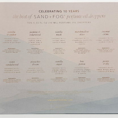 The back of a Sand + Fog perfume oil droppers box celebrating 10 years of the product, featuring a grid of ten different fragrance names and descriptions in a light beige color on a white background.