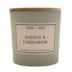 Candle with 'Saddle & Cardamom' label by SAND + FOG on a white background