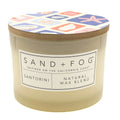 Santorini candle with a patterned lid labeled 'Sand + Fog' on a white background