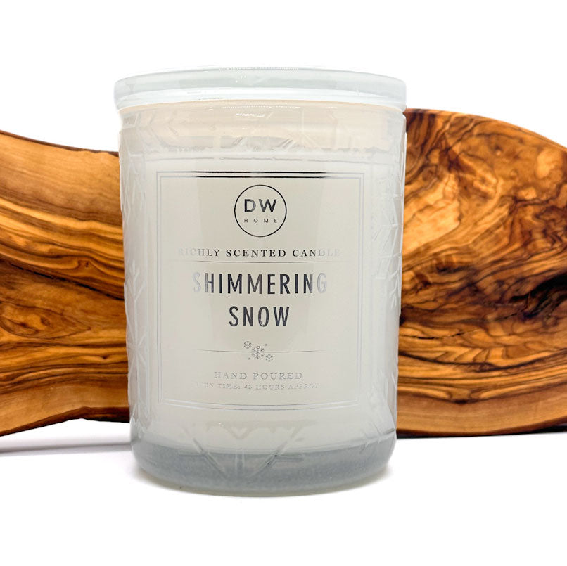 DW Home scented candle labeled 'Shimmering Snow' by DW on a wooden surface