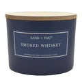 Navy blue candle with a wooden lid labeled 'Sand + Fog Smoked Whiskey' on a white background