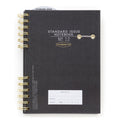 Standard Issue No12 black notebook with gold spiral binding on a white background