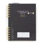 Standard Issue No12 black notebook with gold spiral binding on a white background